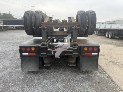 Rear view of a used lowboy trailer showing tandem axles and tires, with suspension frame and mudflaps.