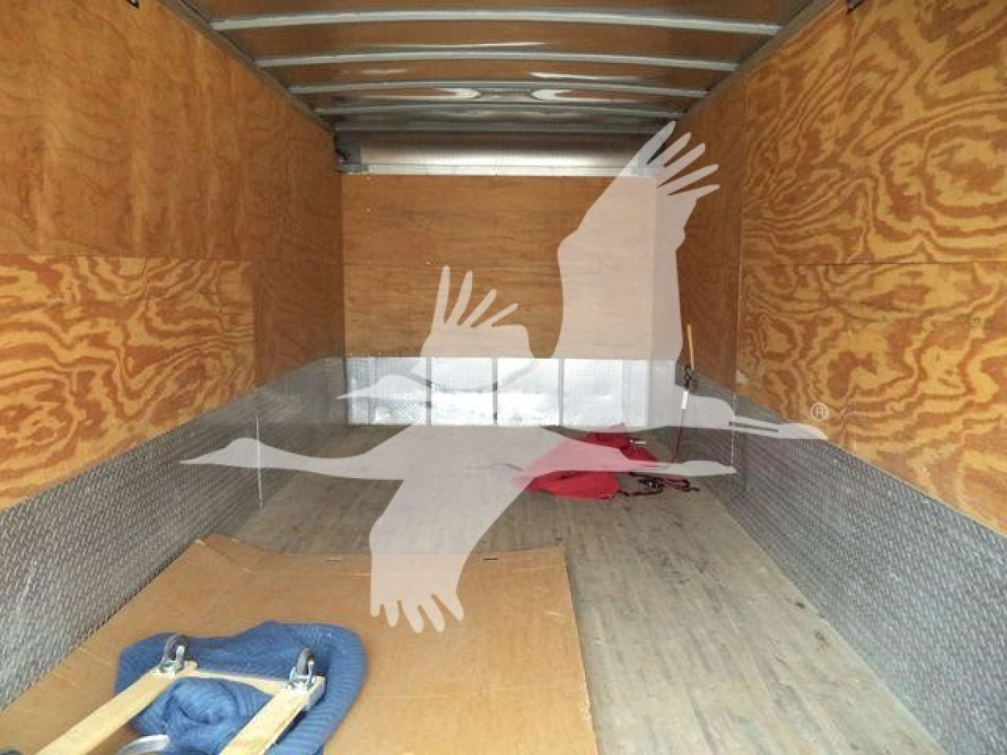 Truck cargo area showing wooden walls and metal lining with a few items on the floor; silhouette watermark obscures some of the space.