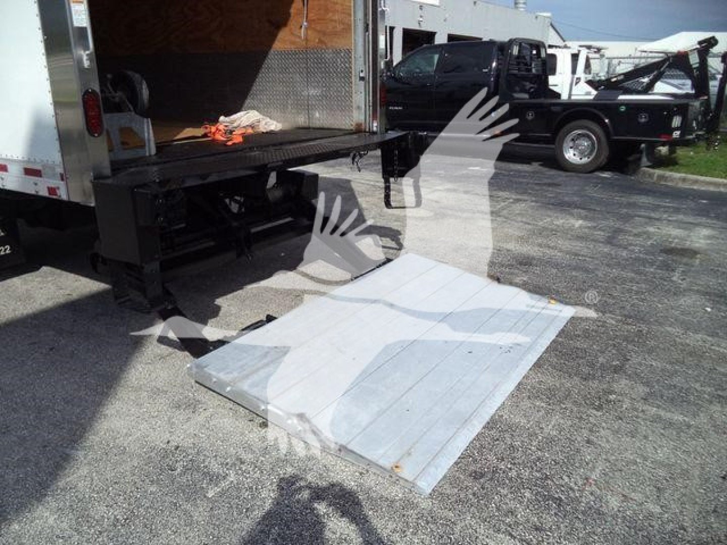 Isuzu NPRR box truck with fold-down aluminum ramp/step extended from rear, loading area open.