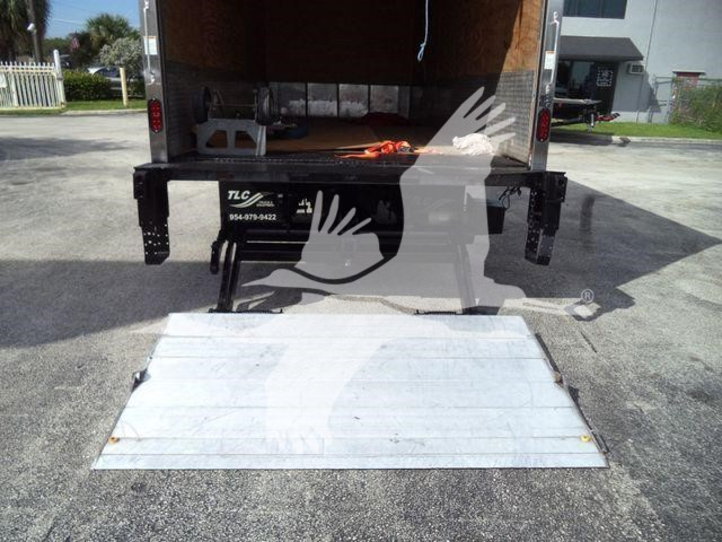 Isuzu NRR box truck rear with lowered aluminum ramp and open cargo area; rear loading area visible.
