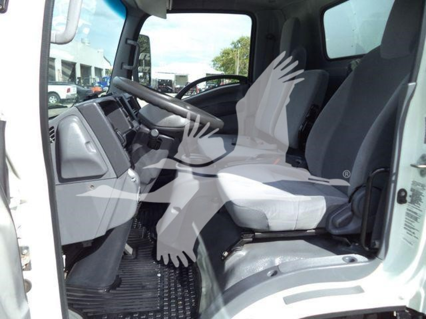 Isuzu NPR/NRR cab interior view showing driver and passenger seats, steering wheel, dashboard, and floor mat in a box truck