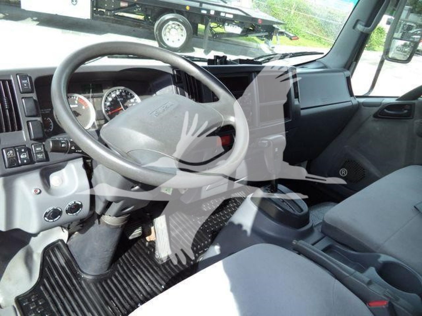 Isuzu NPRR cab interior showing steering wheel and dashboard view with center console and driver seat.