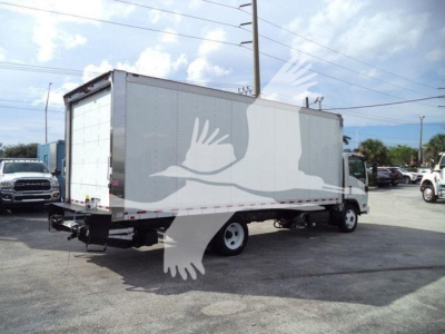 Isuzu NPR/NRR box truck seen from rear-left side, cargo box with roll-up rear door and underride bumper, street scene in background.
