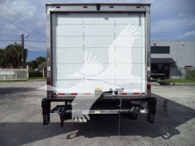 Isuzu NPR box truck rear view showing closed roll-up cargo door and undercarriage with hitch and PTO components.