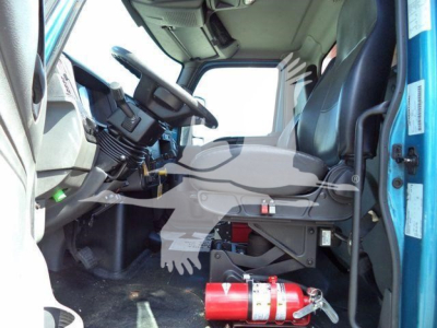 Interior of 2020 International MV cab showing steering wheel, driver seat, pedals, and dashboard with some equipment under dash.