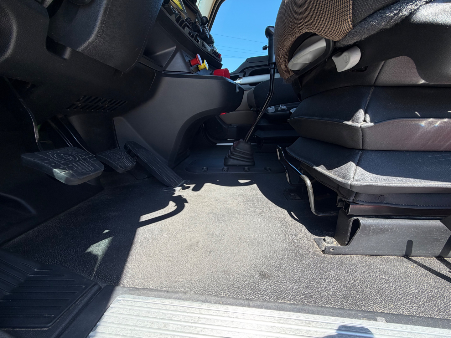 Kenworth T680 interior cabin floor area with driver and passenger seats, center console, and pedals visible.