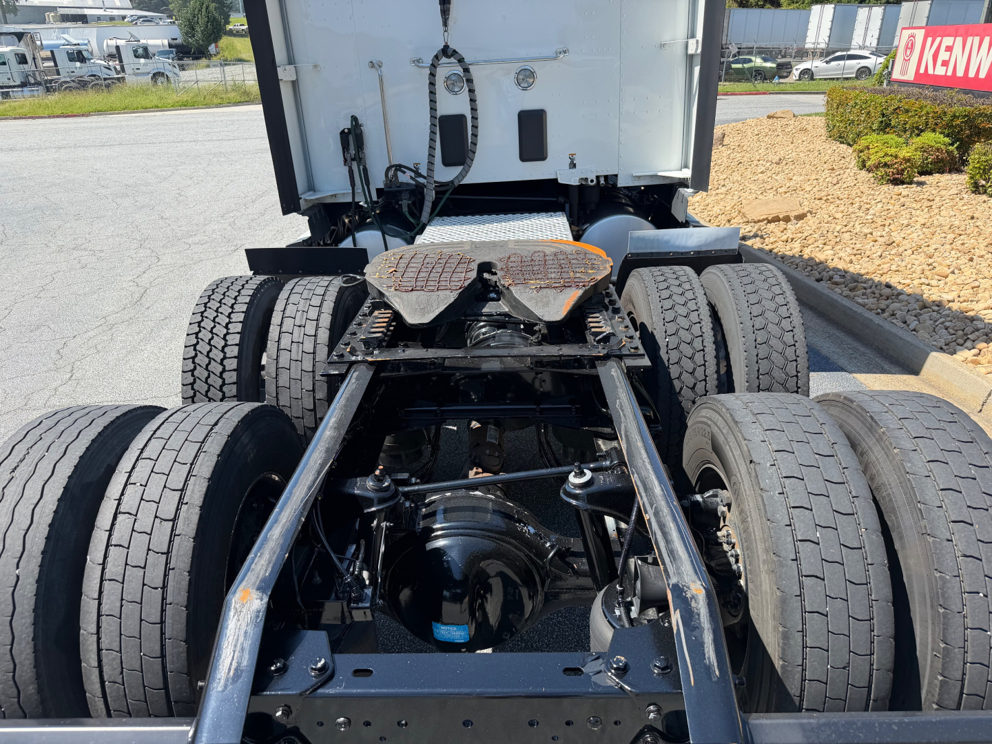 Kenworth T680 tractor rear view showing fifth wheel, dual rear axles, and drive axle housing with suspension components.