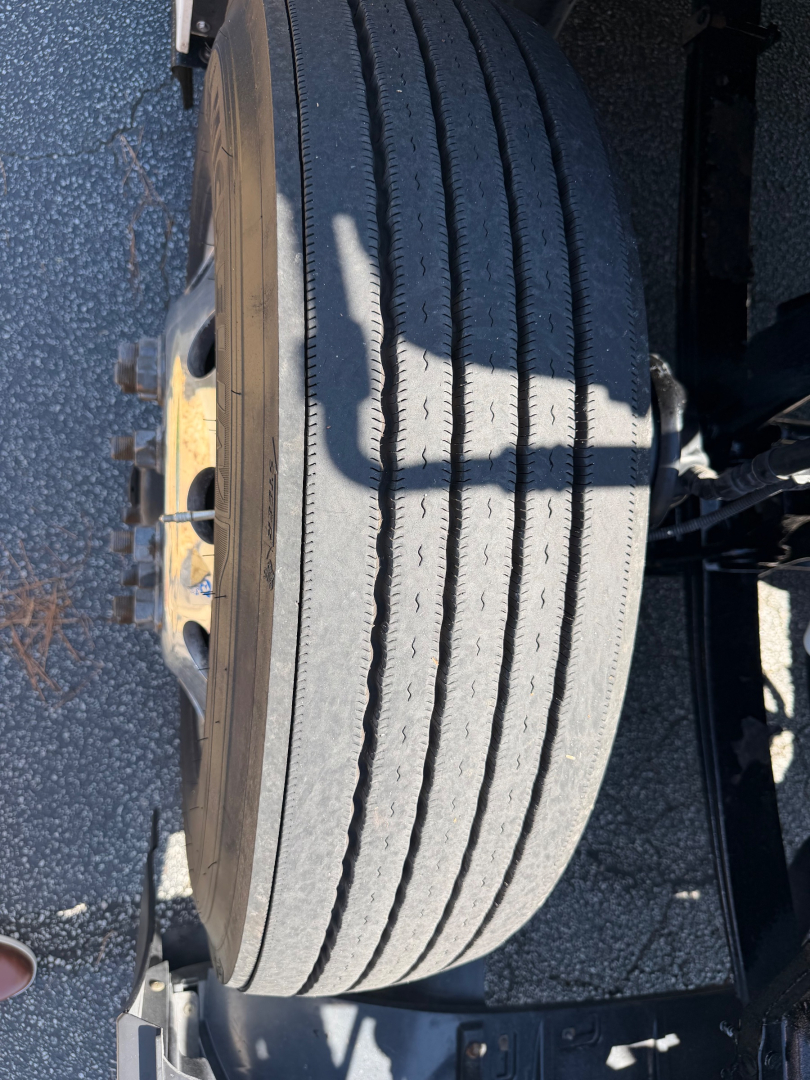 Tire and wheel assembly of a Kenworth truck showing a large radial tire and yellow wheel hub.