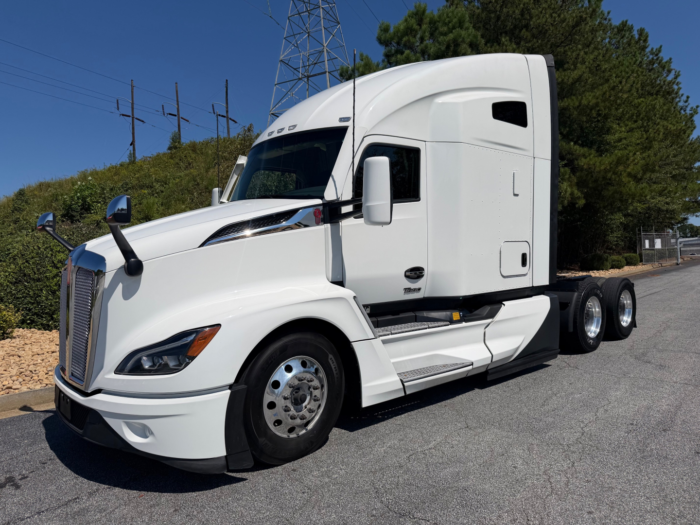 Kenworth T680 tractor-trailer in white, front passenger-side view, with sleeper cab and dual rear axles.