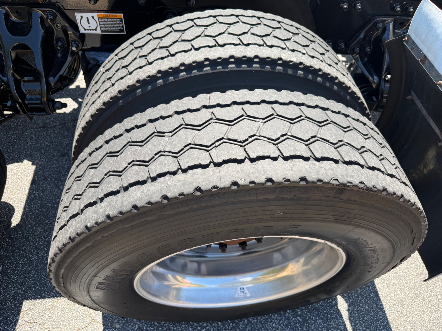 Truck wheel and dual rear tires of a 2023 Kenworth T680 showing tread pattern and chrome wheel hub.