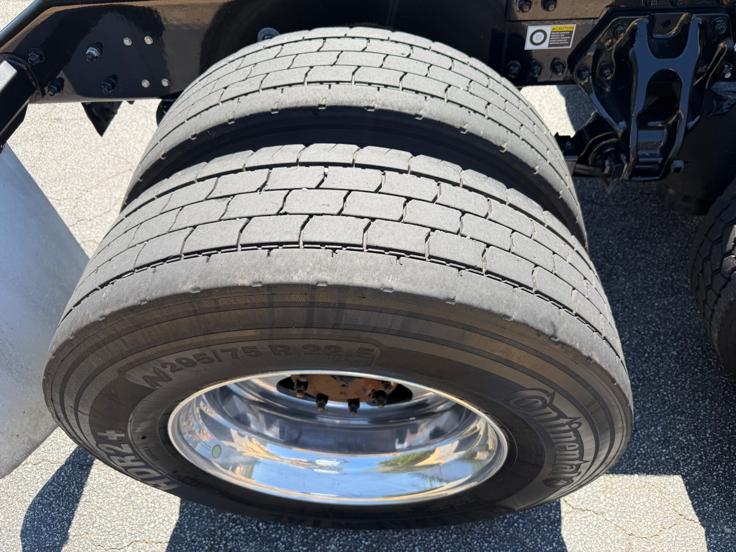 Kenworth T680 wheel and dual rear axle area with tire tread and chrome rim; visible tire sidewall shows printed numbers.