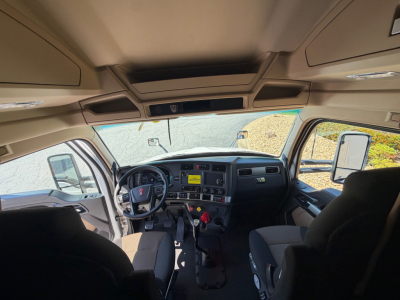 Kenworth T680 truck cabin interior view from driver seat showing dashboard, steering wheel, and two front seats.