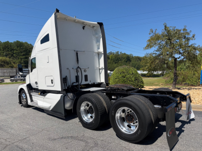 Kenworth T680 tractor in a parking lot, side view showing cab and rear chassis with dual rear axles and fifth-wheel, no trailer attached.