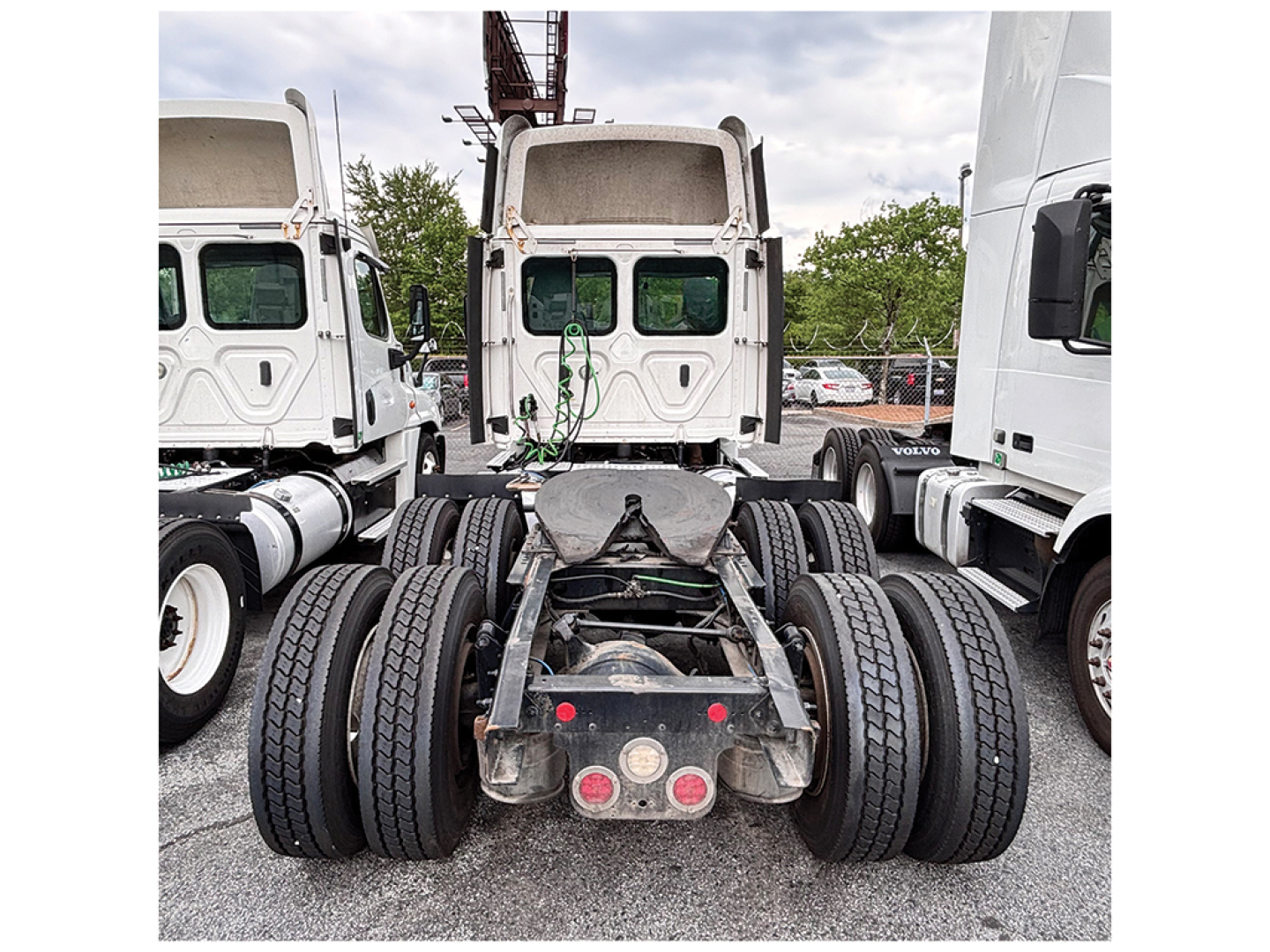 Truck rear view showing fifth wheel hitch and dual rear axles on a Freightliner Cascadia125 tractor with dual tires and mud flaps.
