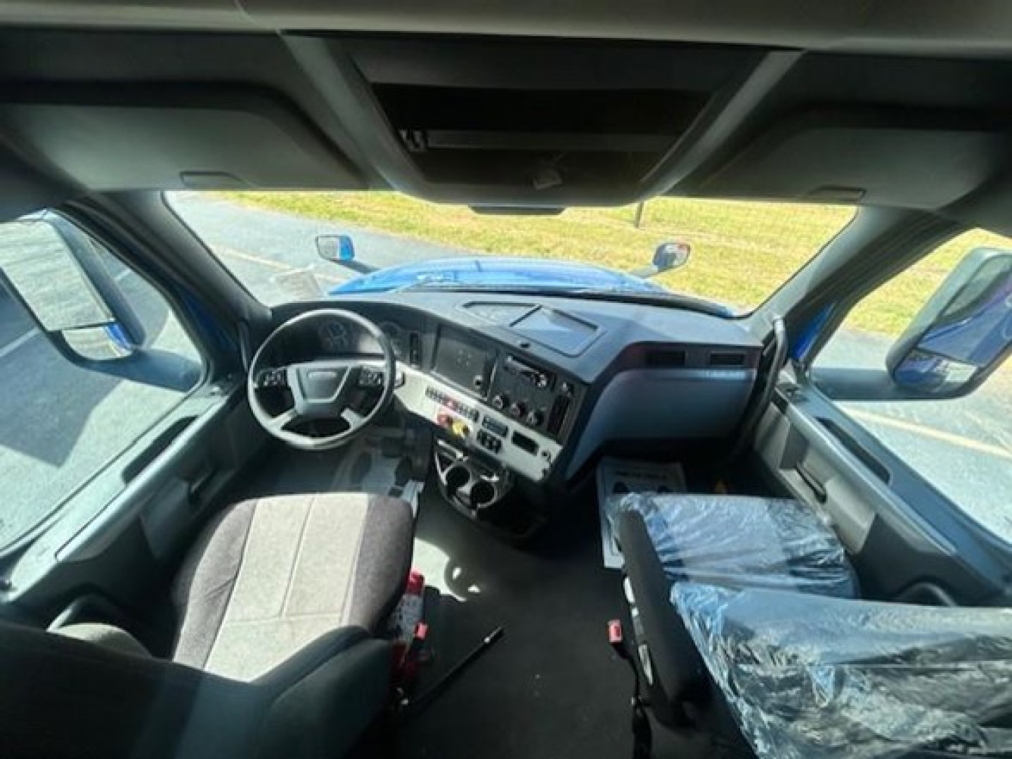 Cab interior of a Freightliner Cascadia 126 from the driver's perspective with steering wheel, dashboard, and seating visible.