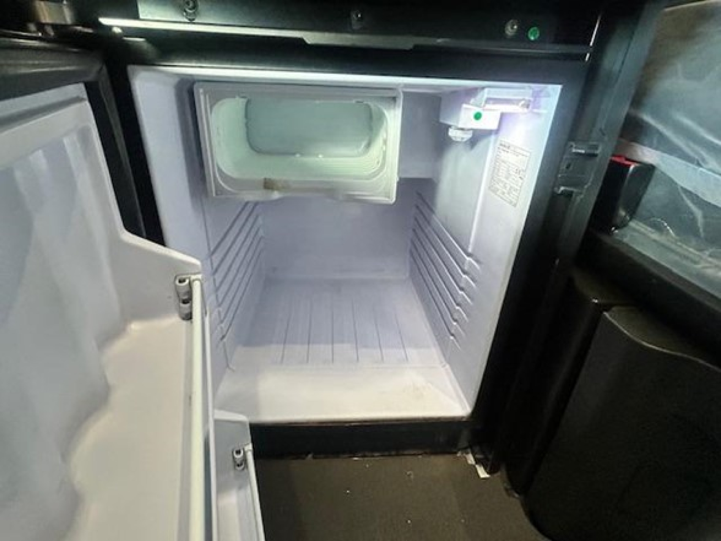 Truck cab interior showing open refrigerator/freezer compartment with empty freezer space and door open