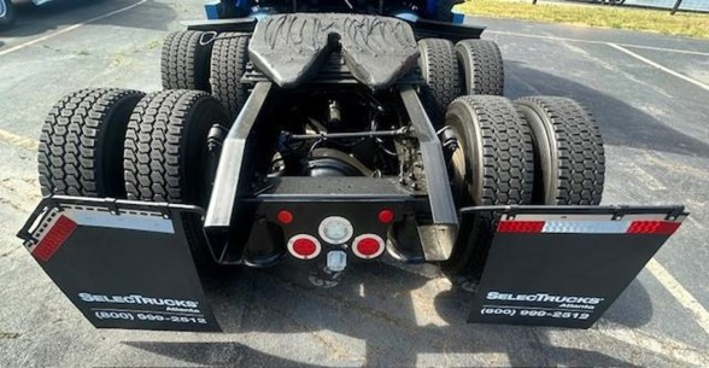 Rear view of a Freightliner Cascadia 126 tractor show with dual rear axles, fifth wheel, and mud flaps displaying dealership contact numbers.