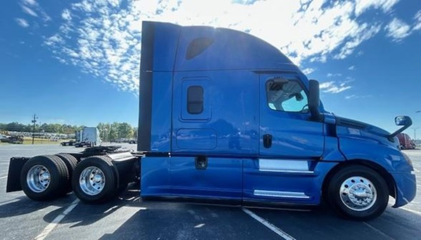 Freightliner Cascadia 126 sleeper tractor side view in blue with three rear axles and chrome wheels.