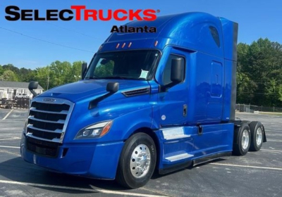 Freightliner Cascadia 126 daytime view showing blue sleeper tractor in parking lot.