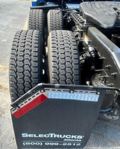 Truck rear dual wheels and fender from a Freightliner Cascadia shown; visible tire tread and chassis components.