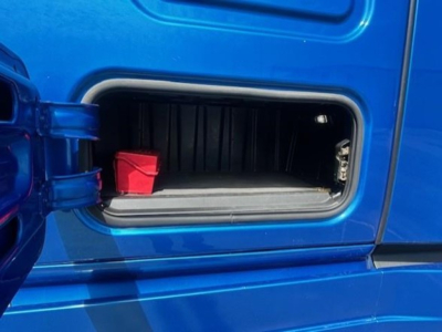 Freightliner Cascadia 126 fuel door/opening showing red battery disconnect cover and storage pocket.