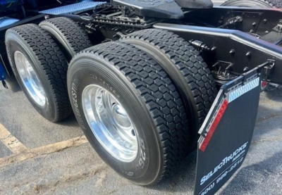 Freightliner Cascadia 126 dual rear axles with large heavy-duty tires and wheel rims, visible chassis and mudflap.