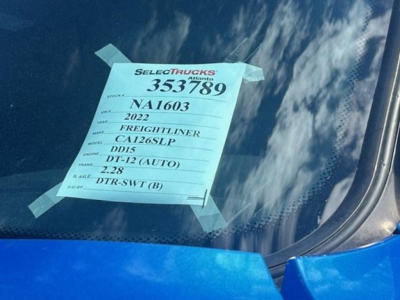 Vehicle window with a blue SelectTrucks sticker showing stock number 353789, year 2022 Freightliner Cascadia 126SLP, VIN 3AKJHHDR9NSNA1603, model details, and DT-12 engine info.