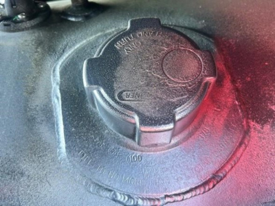 Truck fuel tank cap on Freightliner Cascadia engine bay showing circular filler with embossed text.