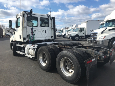 Truck chassis and cab of a Freightliner Cascadia126 tractor with dual rear axles, white cab, exposed fifth wheel area, and parked in a lot.