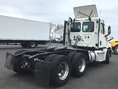 Truck tractor in-service showing rear chassis and dual rear axles with mud flaps and fifth wheel area, cab with sleeper and open hood, Freightliner Cascadia126 styling.