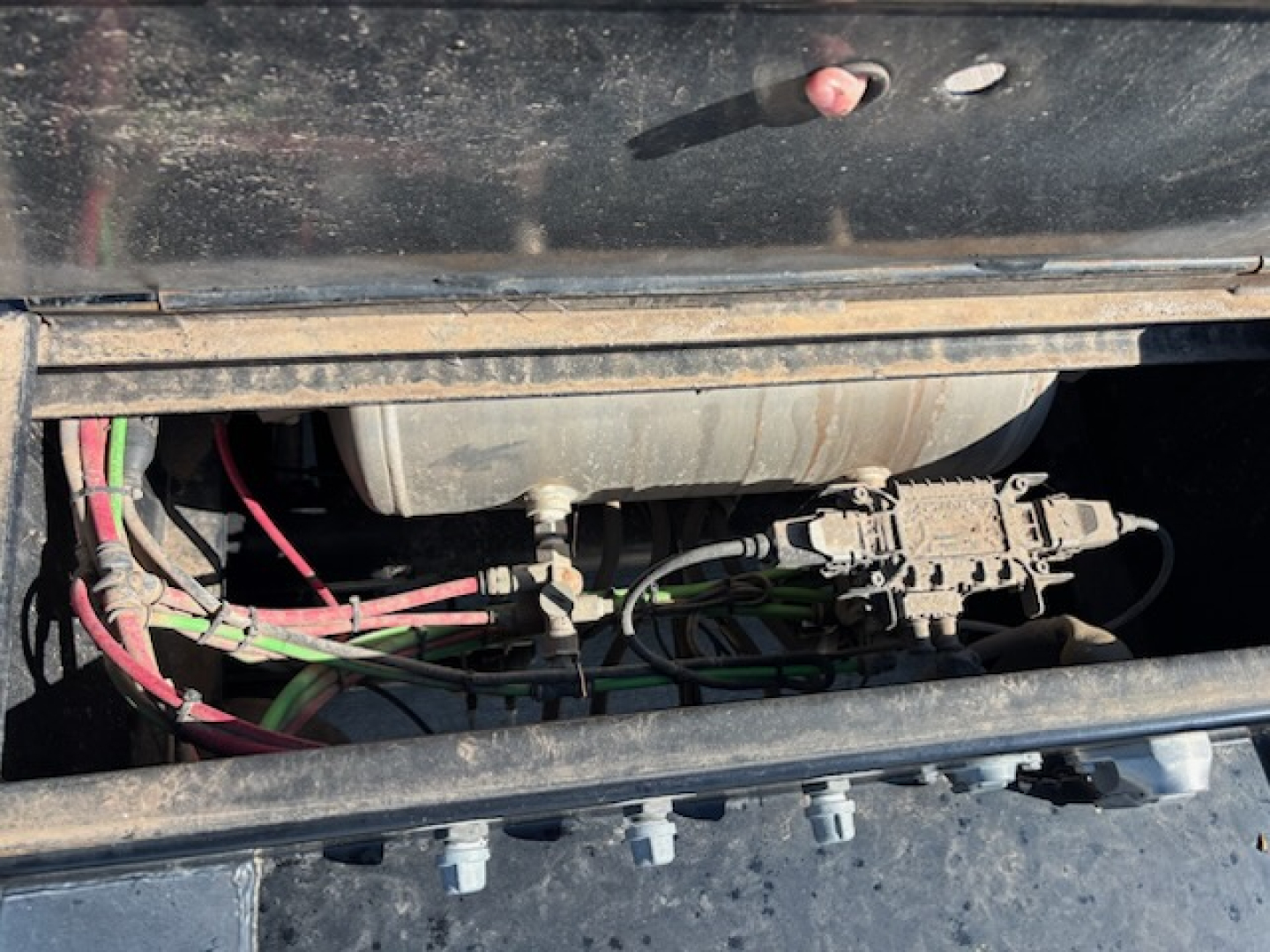 Agricultural trailer engine bay visible with wiring harnesses and a cylindrical component; no legible text or labels clearly readable.
