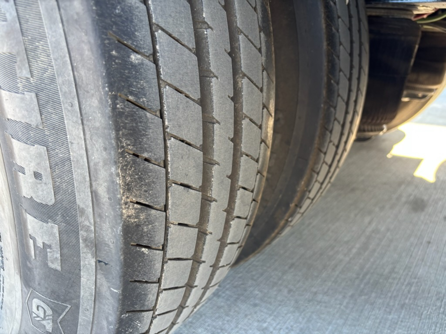 Trailer axle and tire view showing tread pattern and sidewall markings.