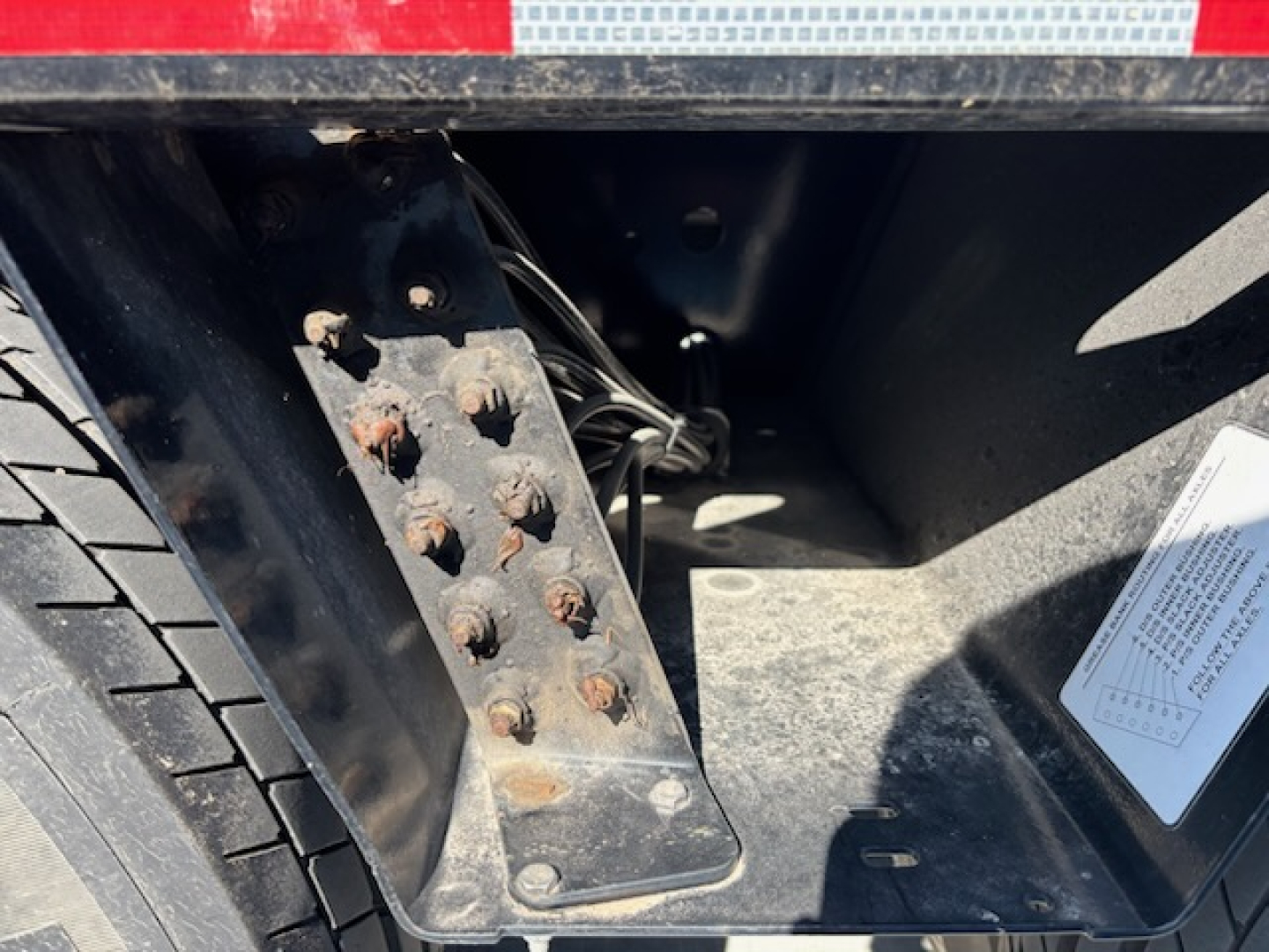 Trailer rear wheel well with black metal step and visible bolts and wiring harness inside.