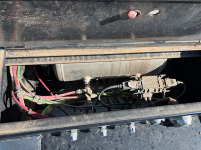 Agricultural trailer engine bay visible with wiring harnesses and a cylindrical component; no legible text or labels clearly readable.