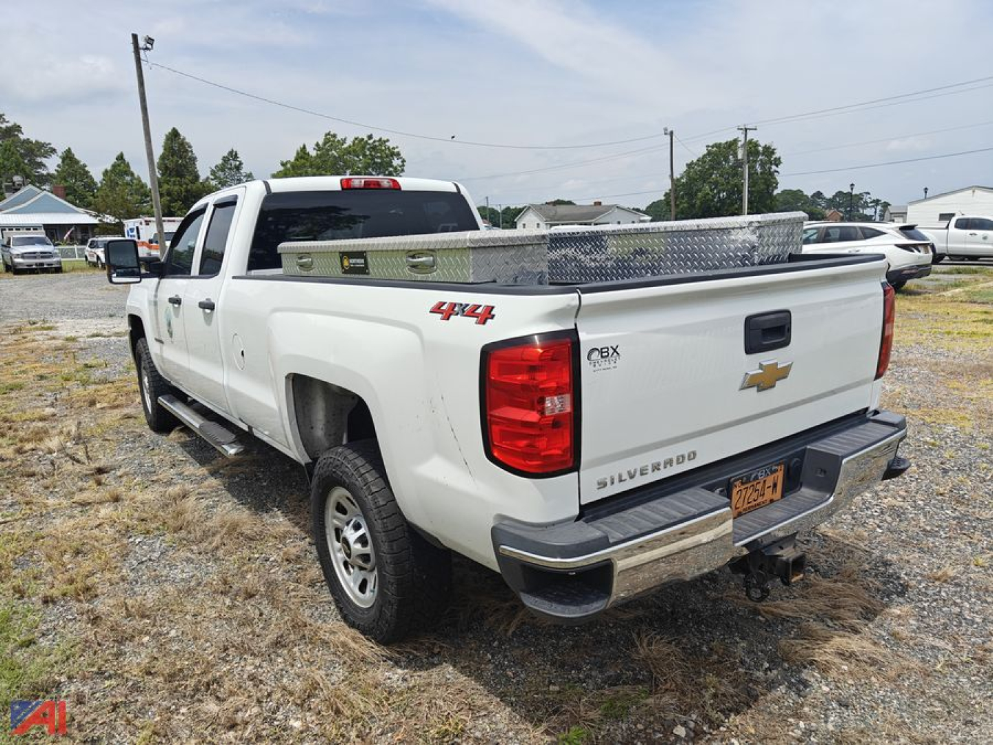 Chevrolet Silverado 2500HD extended cab pickup truck rear side view showing truck bed and chrome rear bumper in a gravel lot.
