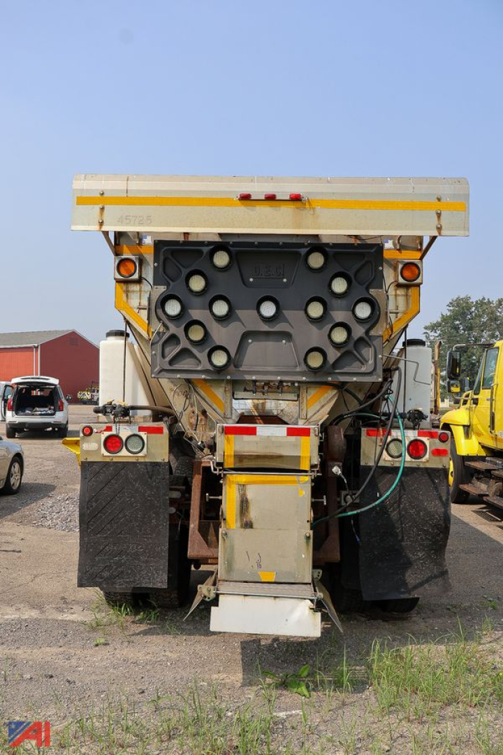 Rear view of a Western Star 4700 SF stake truck showing plow and spreader attachments, back of truck with tailgate and hydraulic components.