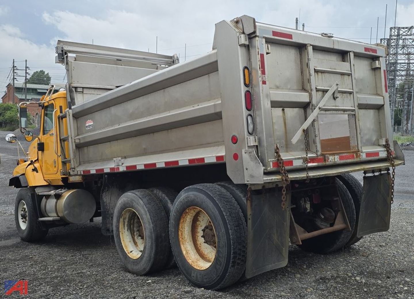 Dump truck rear/side view showing dump body and dual rear axles with tires.