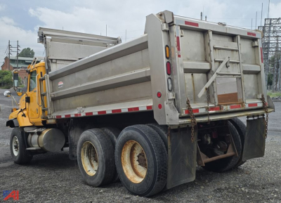 Dump truck rear/side view showing dump body and dual rear axles with tires.