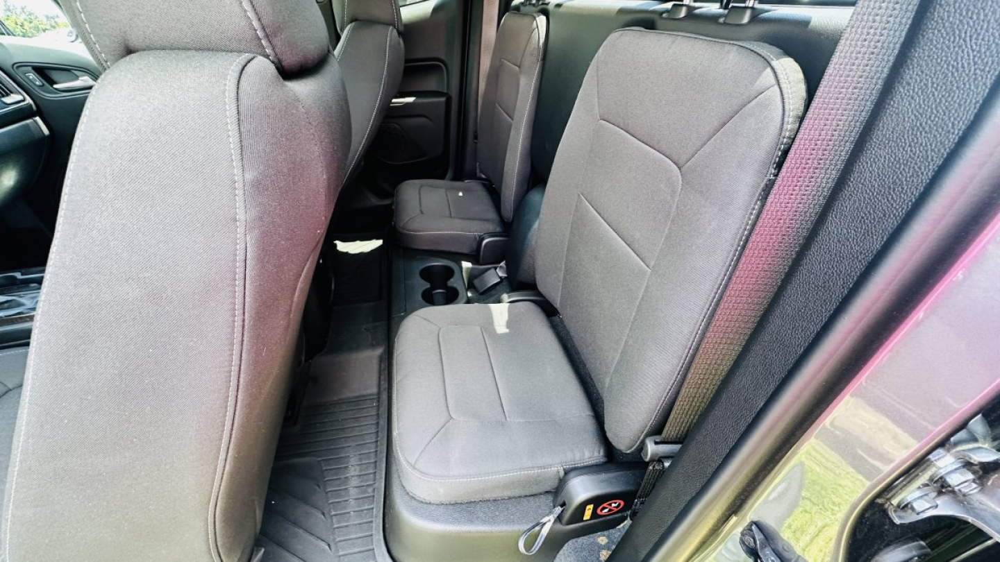 Interior of 2021 GMC Canyon front and rear seating area with gray cloth seats and center cup holders visible.