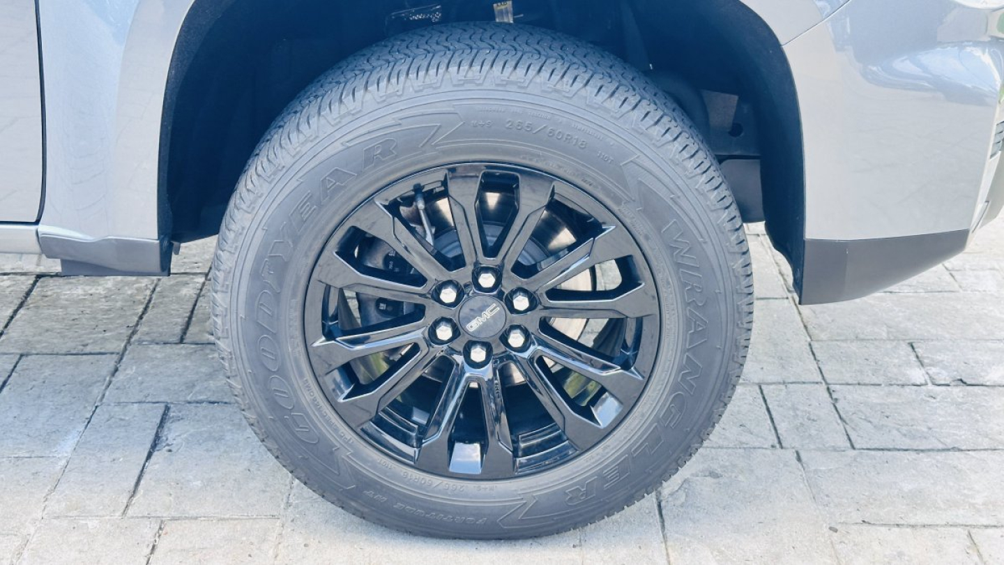 Truck wheel and fender of a 2021 GMC Canyon showing black multi-spoke alloy wheel and tire tread.