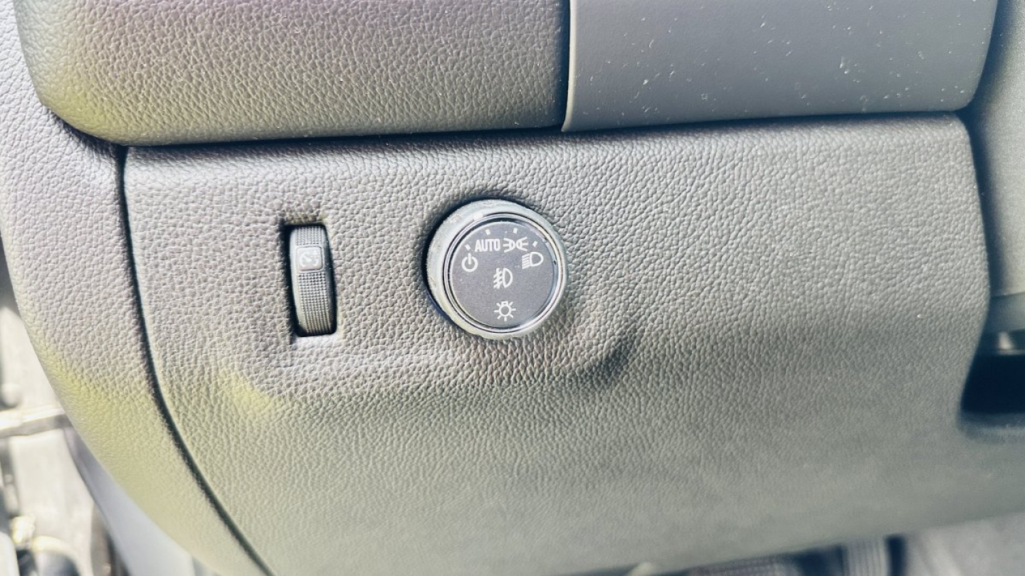 GM vehicle dash panel showing dial for headlights with Auto position and fog light symbol near a small switch.