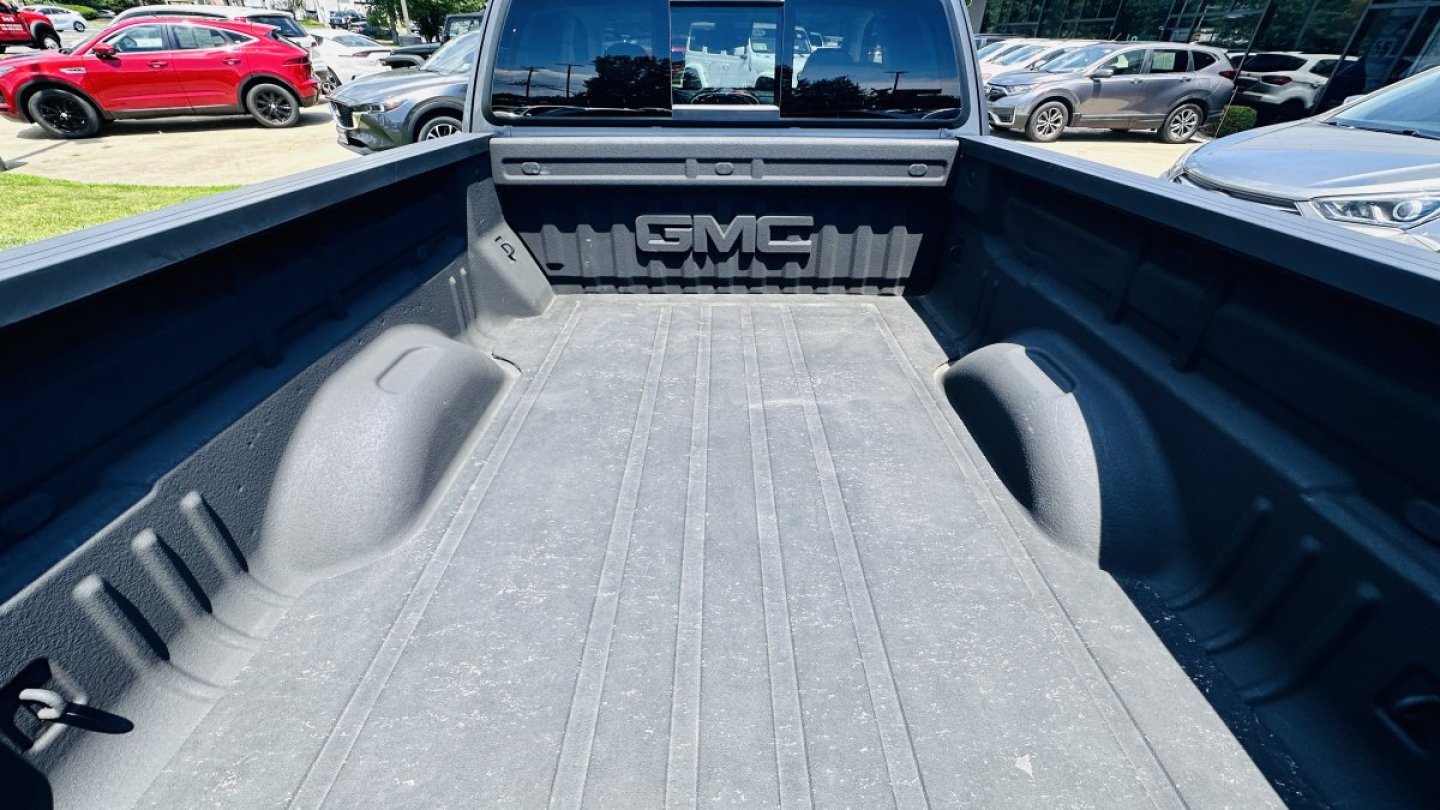 Pickup truck bed in a GMC Canyon with textured bed liner and GMC logo tailgate embossing visible.