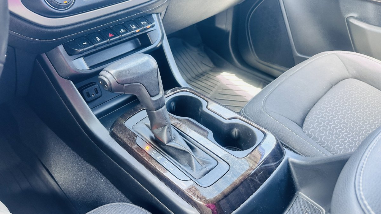 Gear selector console of a 2021 GMC Canyon with shift lever, cup holders, and center console visible.