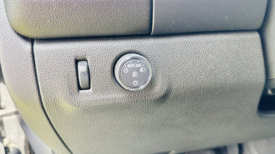 GM vehicle dash panel showing dial for headlights with Auto position and fog light symbol near a small switch.