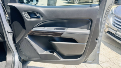 GMC Canyon 2021 interior door panel view showing armrest with wood trim and speaker grille.