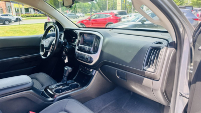 GMC Canyon 2021 interior view from driver side with dashboard, steering wheel, center console, and touchscreen display.