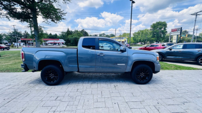 2021 GMC Canyon crew cab pickup side view showing gray exterior, black aftermarket wheels, and extended bed.