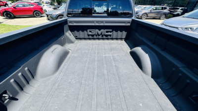 Pickup truck bed in a GMC Canyon with textured bed liner and GMC logo tailgate embossing visible.