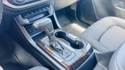 Gear selector console of a 2021 GMC Canyon with shift lever, cup holders, and center console visible.
