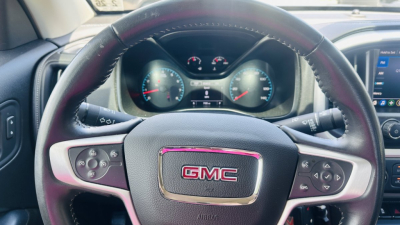 GMC steering wheel and instrument cluster in cabin showing GMC emblem and dashboard controls.